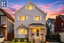 Two-story residence featuring light-colored horizontal siding and a prominent gabled roofline - 14 Niagara Street, Hamilton, ON 