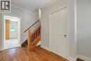 Wood-finish flooring extending into the foreground, a wooden staircase with balusters and handrail, and light gray painted walls - 14 Niagara Street, Hamilton, ON 
