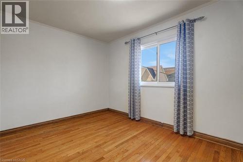 Interior room featuring wood-finish flooring, white walls, and a window with white trim - 14 Niagara Street, Hamilton, ON 