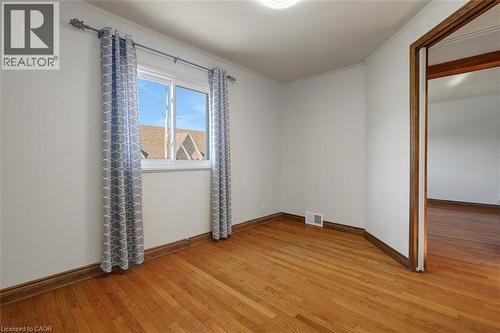 Room featuring wood-finish flooring, white painted walls, a double-hung window, and wood trim - 14 Niagara Street, Hamilton, ON 