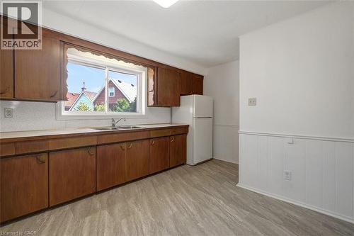 Kitchen featuring a double basin sink, ample wood cabinetry, light-toned countertops, and wood-finish flooring - 14 Niagara Street, Hamilton, ON 