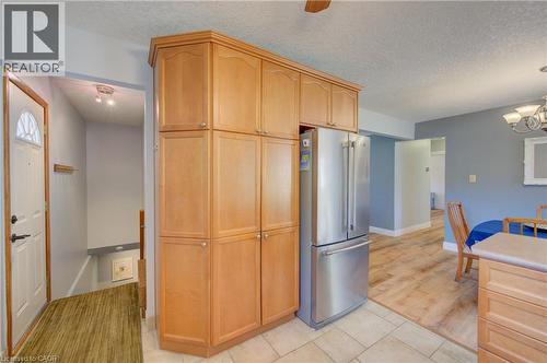 Light wood-finish cabinetry providing ample storage, complemented by a stainless steel refrigerator - 251 Union Street E, Waterloo, ON 