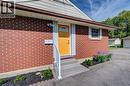 Brick exterior with contrasting yellow entry door, concrete steps, white handrail, and front-facing landscape bed - 251 Union Street E, Waterloo, ON 