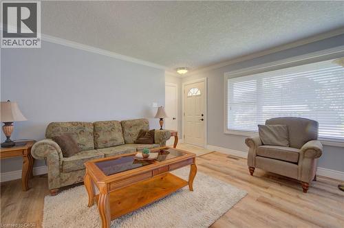 Living area featuring light wood-finish flooring, light blue wall paint, white crown molding, and a white front door with a decorative glass insert - 251 Union Street E, Waterloo, ON 