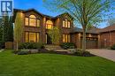 Two-story brick exterior residence featuring a front-facing attached garage, arched window accents, a paved driveway, and mature landscaping - 28 Deerview Avenue, Ancaster, ON 