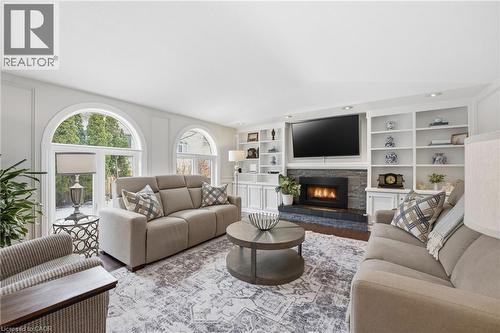 Living area featuring a fireplace, built in shelves, and wood finished floors - 28 Deerview Avenue, Ancaster, ON 