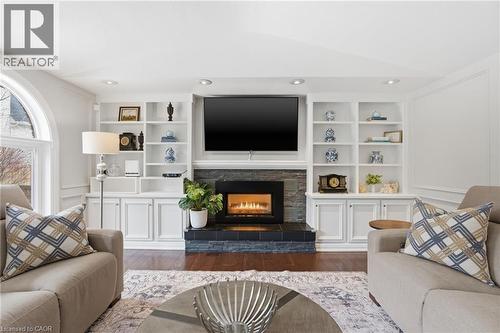 Living area featuring built in shelves, dark wood finished floors, a fireplace, and lofted ceiling - 28 Deerview Avenue, Ancaster, ON 