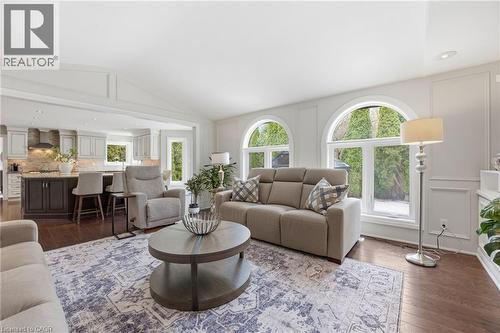 Living area with lofted ceiling, dark wood-style flooring, recessed lighting, and a decorative wall - 28 Deerview Avenue, Ancaster, ON 
