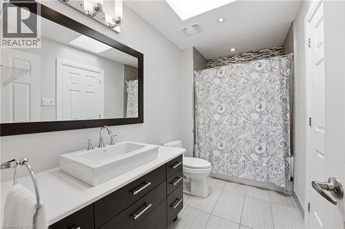 Bathroom with vanity, a skylight, shower / bath combo, and light tile patterned floors - 28 Deerview Avenue, Ancaster, ON 