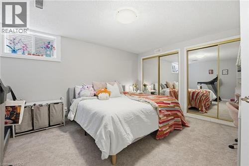 Bedroom featuring two closets, light carpet, and a textured ceiling - 28 Deerview Avenue, Ancaster, ON 