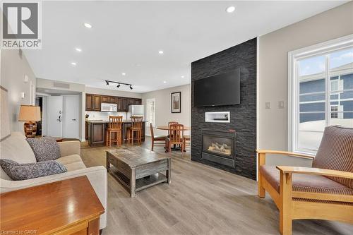 Living area featuring light wood-style floors, a stone fireplace, and track lighting - 90 Highland Drive Unit# 2014/15, Simcoe, ON 
