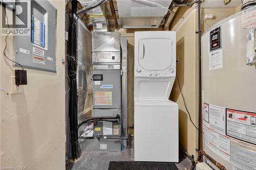 Laundry area with water heater, stacked washer and dryer, electric panel, and heating unit - 90 Highland Drive Unit# 2014/15, Simcoe, ON 