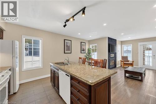 Kitchen with plenty of natural light, light stone counters, white appliances, rail lighting, and an island with sink - 90 Highland Drive Unit# 2014/15, Simcoe, ON 