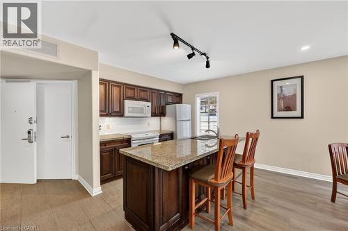 Kitchen with rail lighting, white appliances, backsplash, light stone counters, and a breakfast bar area - 90 Highland Drive Unit# 2014/15, Simcoe, ON 