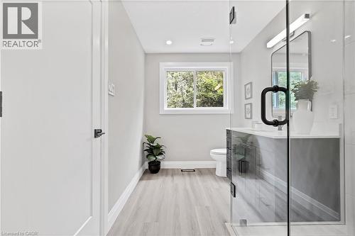 Bathroom featuring a glass-enclosed shower, a single vanity with a white countertop, and light wood-finish flooring - 71 Blucher Street Unit# G, Kitchener, ON 