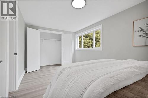 Bedroom featuring light wood-finish flooring, a white window frame, and a built-in closet with bifold doors - 71 Blucher Street Unit# G, Kitchener, ON 