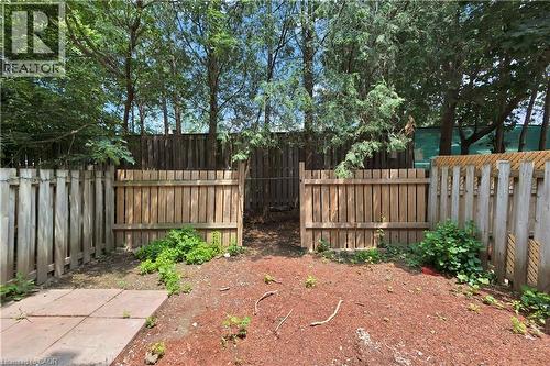 Enclosed backyard featuring wood fencing, a partial concrete patio, and a natural ground cover of mulch and greenery - 71 Blucher Street Unit# G, Kitchener, ON 