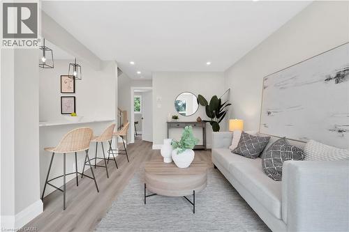 Open-concept living area featuring light wood-finish flooring, recessed lighting, and a white countertop breakfast bar with contemporary pendant lighting - 71 Blucher Street Unit# G, Kitchener, ON 