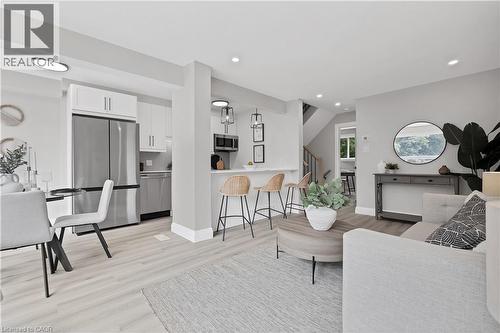 Open-concept living area featuring light wood-finish flooring, recessed lighting, a kitchen with stainless steel appliances, white cabinetry, and a breakfast bar - 71 Blucher Street Unit# G, Kitchener, ON 