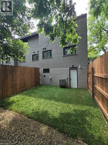 Private fenced yard featuring a manicured lawn, gravel border, and a wood privacy fence - 71 Blucher Street Unit# G, Kitchener, ON 