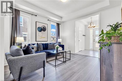 Bright living area featuring light wood-finish flooring, white walls, and a tray ceiling - 101 Westfield Crescent, Waterdown, ON 