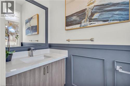 Main Floor Powder Room- Vanity featuring a wood-finish cabinet with double doors, under-mount sink, and a light-toned countertop - 101 Westfield Crescent, Waterdown, ON 