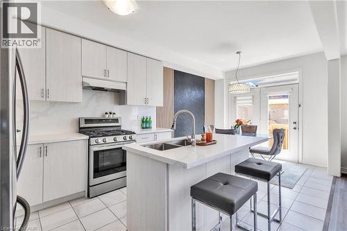 Contemporary kitchen featuring light wood-finish cabinetry, stainless steel appliances, and a central island with a sink - 101 Westfield Crescent, Waterdown, ON 