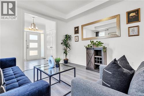 Living and Foyer-Light-filled entry area featuring a modern front door with frosted glass panels, a contemporary chandelier, and tiled flooring - 101 Westfield Crescent, Waterdown, ON 