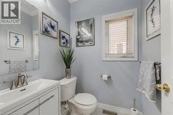 Powder room featuring a white vanity with integrated sink, brushed nickel faucet, a frameless wall mirror, and a window with white blinds - 