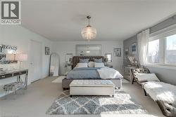 Spacious bedroom featuring light-toned carpeting and a chandelier-style lighting fixture - 