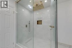 Glass-enclosed shower with white marble-style tile, a linear drain, and a built-in shower niche - 