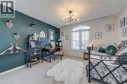 Room featuring a prominent arched window, plush carpeting, modern chandelier, and a built-in wall shelf - 