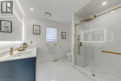 Contemporary bathroom featuring a spacious glass-enclosed shower with gold-tone hardware, a sleek wall-mounted vanity with a single basin, and large format marble-look floor and wall tiling - 
