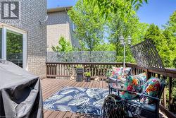 Expansive outdoor deck featuring wood-finish flooring, a dark wood railing, and decorative privacy screens - 