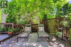 Expansive outdoor deck featuring wood-finish flooring, a lattice privacy screen, and rich natural foliage - 