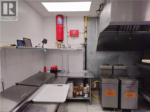 Professional-grade kitchen featuring stainless steel countertops, a commercial-style range hood, gas lines, and white plank-style wall paneling - 71 Ross Street Unit# 2, St. Thomas, ON 