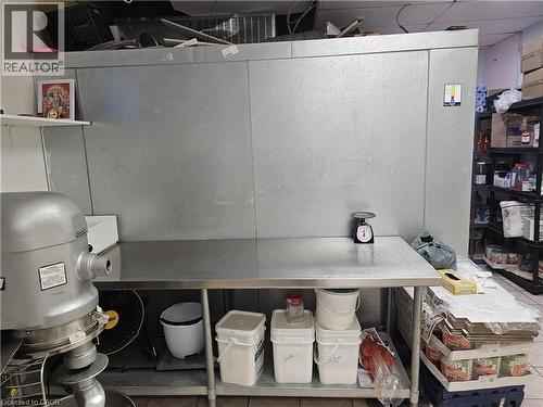 Commercial-grade stainless steel work table with integrated shelving and a large walk-in cooler, featuring additional metal shelving units for storage - 71 Ross Street Unit# 2, St. Thomas, ON 