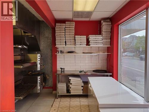 Commercial kitchen space featuring a stainless steel exhaust hood, built-in ovens, white subway tile backsplash, stainless steel preparation table, and a large front window - 71 Ross Street Unit# 2, St. Thomas, ON 