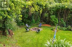 Spacious green lawn with a built-in fire pit surrounded by a wooded perimeter - 