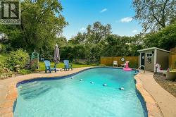In-ground swimming pool with flagstone coping, surrounded by established landscaping and a privacy fence - 