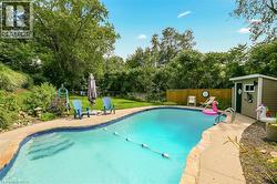In-ground swimming pool with a concrete surround, wood privacy fence, and a dedicated storage shed - 