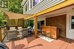 Expansive outdoor deck featuring wood flooring, a built-in wooden bar, and a slatted privacy screen - 