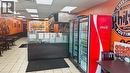 Commercial kitchen space featuring a service counter with a dark wood-finish front, stainless steel overhead exhaust hood, and three glass-front display refrigerators - 2405 Fairview Street, Burlington, ON 