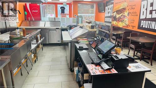 Commercial kitchen space featuring stainless steel appliances, white floor tiling, and a service counter with multiple point-of-sale systems - 2405 Fairview Street, Burlington, ON 