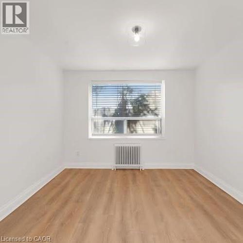 Bright room featuring wood-finish flooring and a large window with horizontal blinds - 57 Mericourt Road Unit# 111, Hamilton, ON - Indoor Photo Showing Other Room