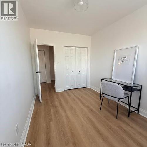 Bright interior space featuring wood-finish flooring, white walls, and a white bi-fold closet - 57 Mericourt Road Unit# 111, Hamilton, ON - Indoor Photo Showing Other Room