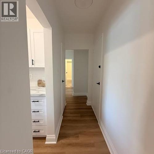 Hallway featuring wood-finish flooring, white baseboards, and white walls - 57 Mericourt Road Unit# 111, Hamilton, ON - Indoor Photo Showing Other Room