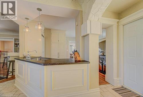 Kitchen island with a dark countertop and undermount sink, illuminated by two clear glass pendant lights - 2032 Coronation Boulevard, Cambridge, ON - Indoor