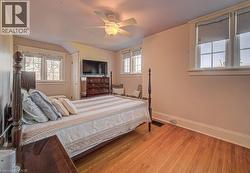 Hardwood flooring throughout featuring multiple windows with white trim and a ceiling fan with integrated lighting - 