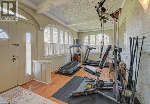 Interior space featuring wood-finish flooring, textured ceiling, arched windows, and a white paneled door with glass inserts - 2032 Coronation Boulevard, Cambridge, ON - Indoor Photo Showing Gym Room